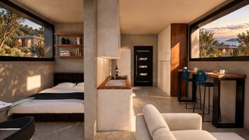Εικόνα 2 από 4: Ο ενιαίος εσωτερικός χώρος της compact κατοικίας: κρεβάτι, κουζίνα και πάγκος φαγητού, με θέα στη θάλασσα